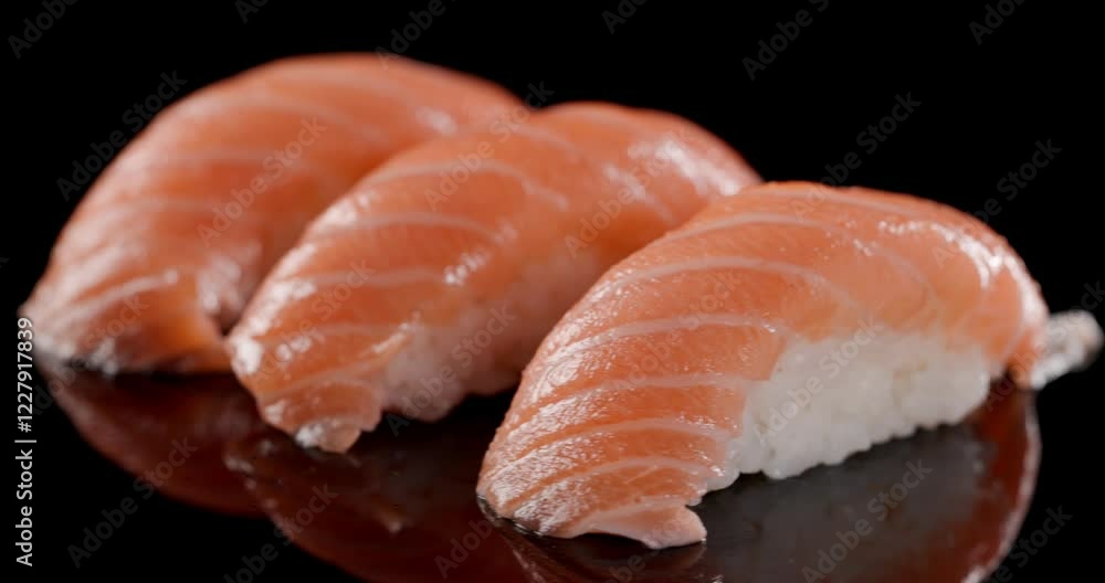 three pieces of japanese food called sushi made out of rice and salmon rotating while isolated on black background three pieces of japanese food called sushi made out of rice and salmon rotating while isolated on black background