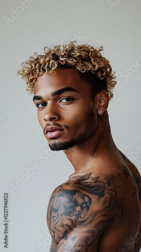 A photograph of an attractive Black man with blonde, curly hair and tattoos
