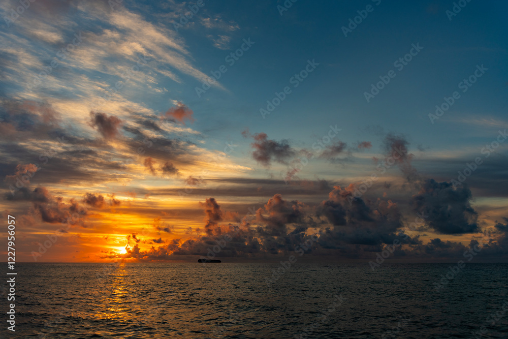 Naklejka premium Early morning sunrise over sea. Ocean sunset on sea beach with sunset sky and seascape with ship. Seascape golden sunrise over the sea. Nature concept. Beautiful twilight. Sea beach