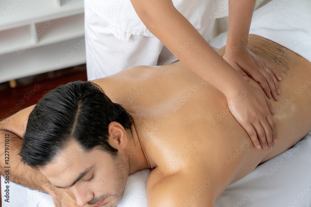 Caucasian man customer enjoying relaxing anti-stress spa massage and pampering with beauty skin recreation leisure in day light ambient salon spa at luxury resort or hotel. Quiescent Caucasian man customer enjoying relaxing anti-stress spa massage and pampering with beauty skin recreation leisure in day light ambient salon spa at luxury resort or hotel. Quiescent