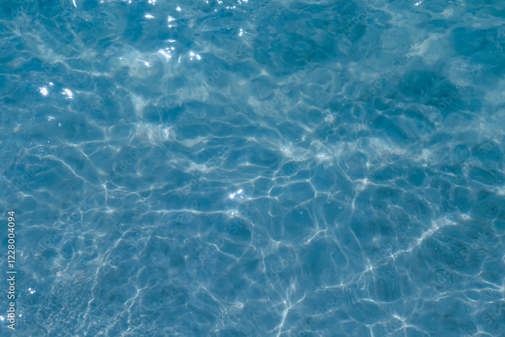 Overhead view of blue water surface abstract. Wave on moving water surface close up in the middle of the screen. Blue ocean water with waves background Overhead view of blue water surface abstract. Wave on moving water surface close up in the middle of the screen. Blue ocean water with waves background