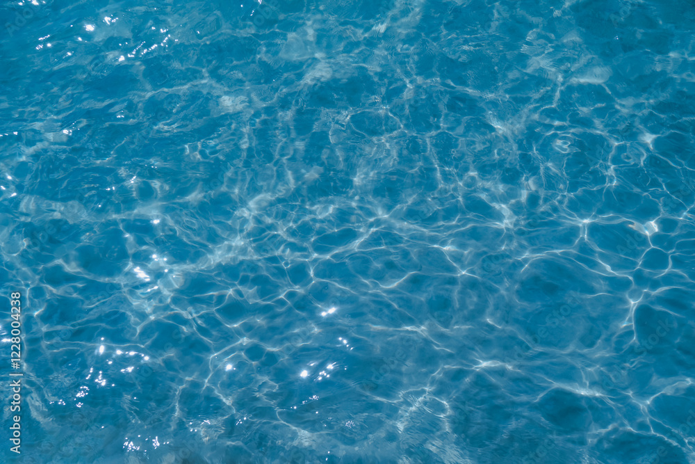 Overhead view of blue water surface abstract. Wave on moving water surface close up in the middle of the screen. Blue ocean water with waves background Overhead view of blue water surface abstract. Wave on moving water surface close up in the middle of the screen. Blue ocean water with waves background
