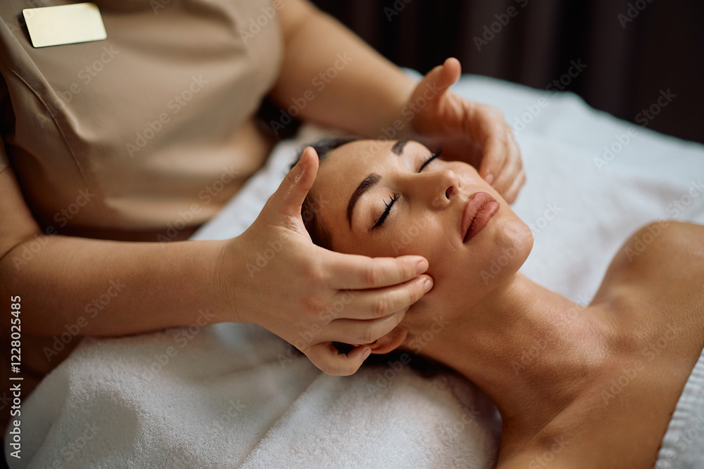 Relaxed woman receiving facial massage during spa treatment. Relaxed woman receiving facial massage during spa treatment.