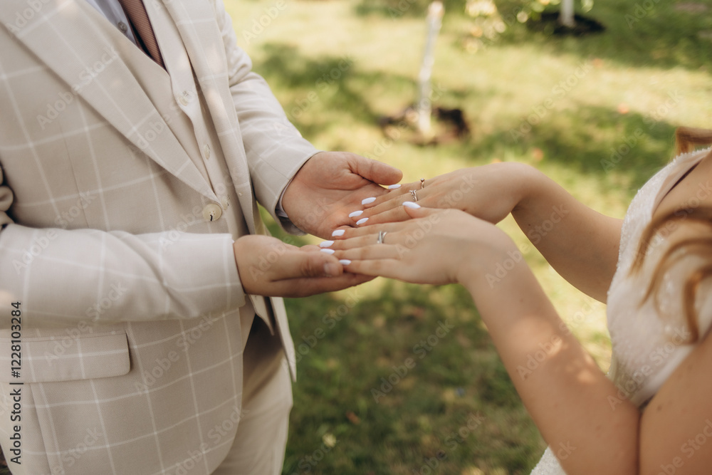 The bride and groom hold hands on their wedding day and put their rings on each other in love on a sunny day The bride and groom hold hands on their wedding day and put their rings on each other in love on a sunny day