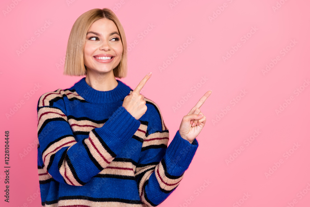 Smiling woman in a striped sweater pointing upward on a pink background Smiling woman in a striped sweater pointing upward on a pink background