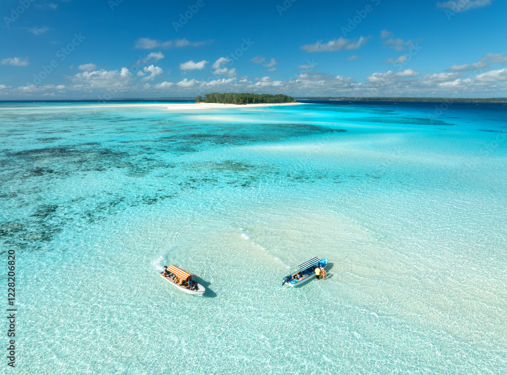 Aerial view of colorful boats and yachts in transparent water on sunny summer day. Mnemba island, Zanzibar. Top view of sandbank in low tide, blue sea, turquoise water, yachts, sky with clouds. Ocean Aerial view of colorful boats and yachts in transparent water on sunny summer day. Mnemba island, Zanzibar. Top view of sandbank in low tide, blue sea, turquoise water, yachts, sky with clouds. Ocean