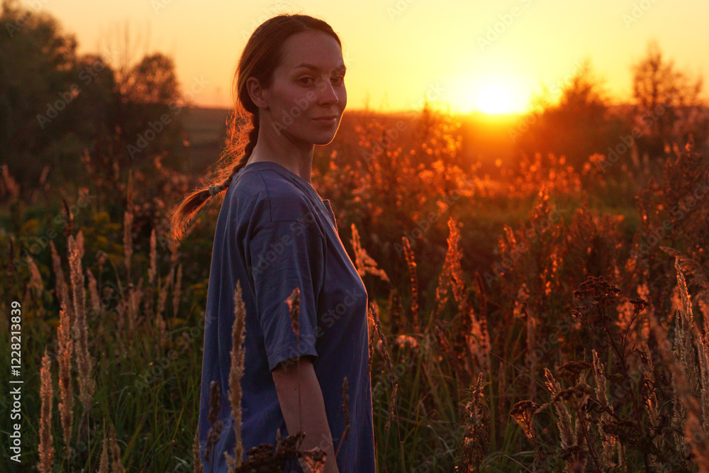 A young woman stands in a sunlit field surrounded by plants during sunset. Her expression is serene and captivating, embodying the beauty of nature. A young woman stands in a sunlit field surrounded by plants during sunset. Her expression is serene and captivating, embodying the beauty of nature.