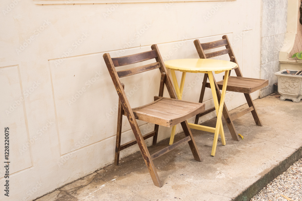 Yellow table and wooden chairs at cozy house or restaurant in garden,modern home decor,Contemporary interior design of dining space,minimal concept. Yellow table and wooden chairs at cozy house or restaurant in garden,modern home decor,Contemporary interior design of dining space,minimal concept.