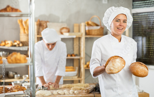 Smiling young girl demonstrating bread in right-angled woven basket in bakehouse photo