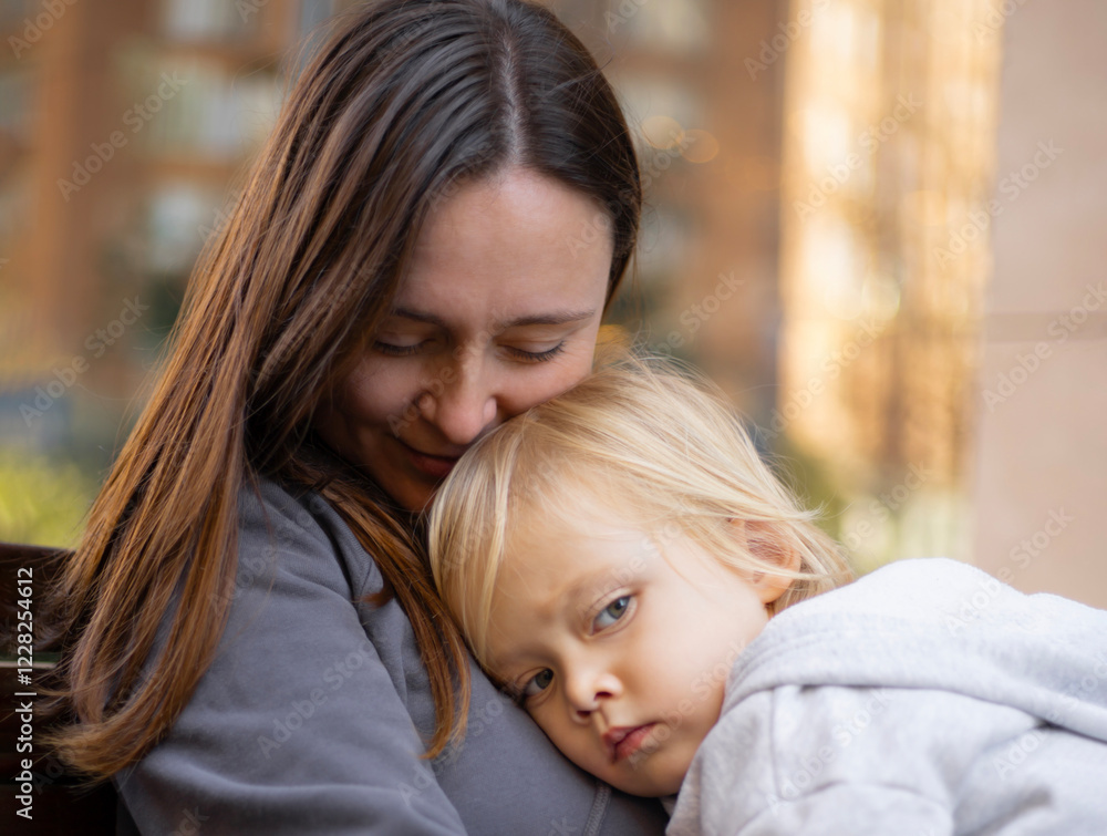 Obraz premium a three-year-old boy rested his head on his mother's shoulder, motherhood