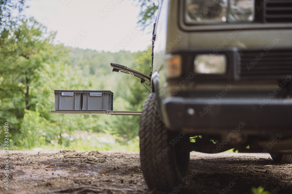 Two plastic euro box on a pull out drawer of a vintage adventure offroad vehicle or motor home, parked outside in a forest