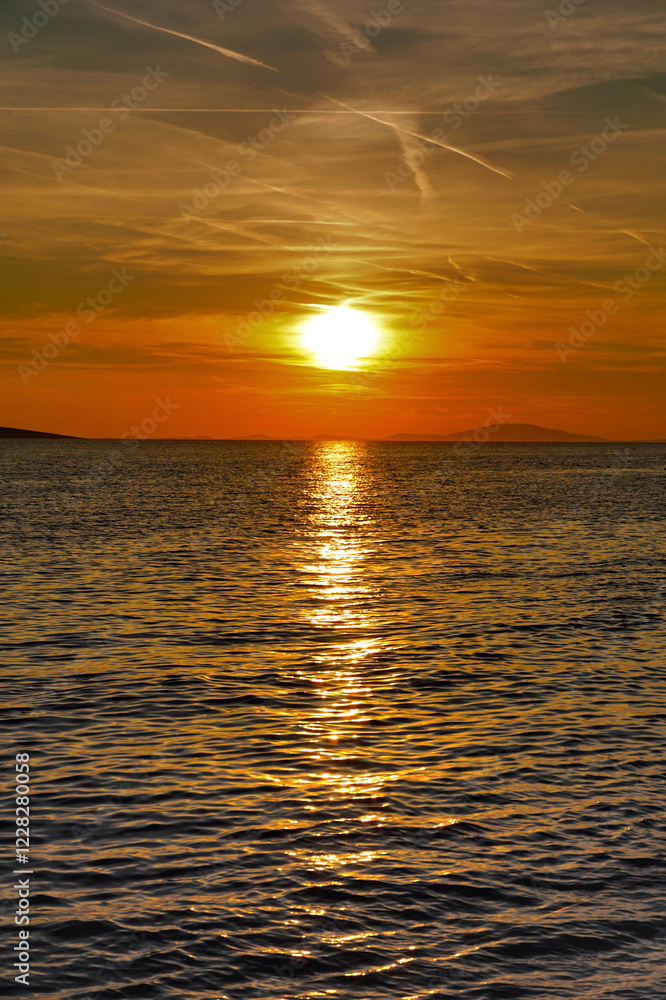 Obraz premium Sea horizon between dramatic sky with clouds and chem trails and shiny and wavy sea surface