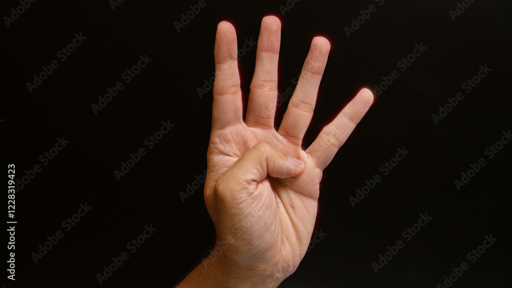Man showing four fingers against a dark background, emphasizing the number four with his hand gesture. Man showing four fingers against a dark background, emphasizing the number four with his hand gesture.