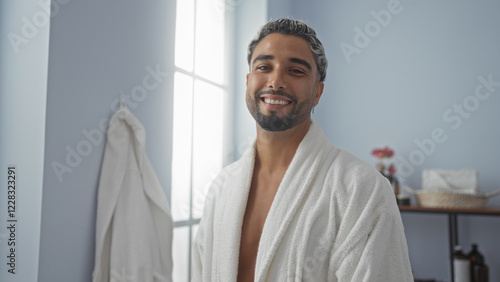 Handsome young arab man with a beard smiling at a wellness spa in a white robe indoors. photo