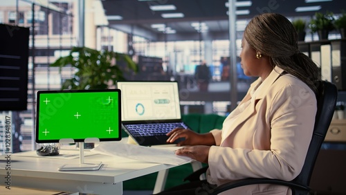 African american empowered woman working with isolated chroma key on tablet, working on planning data analytics or income at her desk. Developing a strategy to increase funds for project. Camera B.
