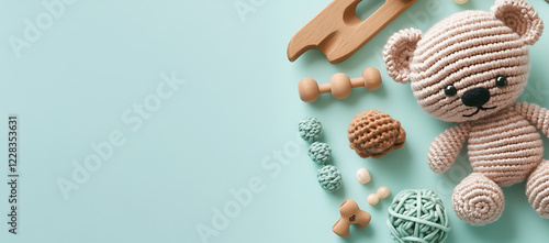 Eco friendly handmade baby toys on a mint background including wooden rattles a crocheted teddy bear and teething beads Copy space image Place for adding text or design photo