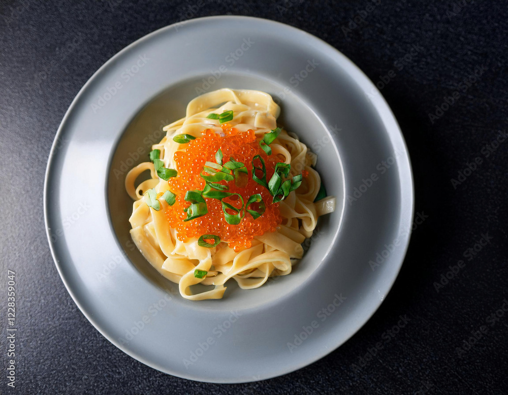 Fresh fettuccine pasta topped with bright orange salmon roe and chopped chives served on a white Fresh fettuccine pasta topped with bright orange salmon roe and chopped chives served on a white