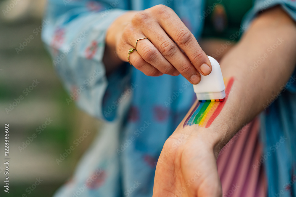 Fototapeta premium Woman painting rainbow flag on arm celebrating pride month