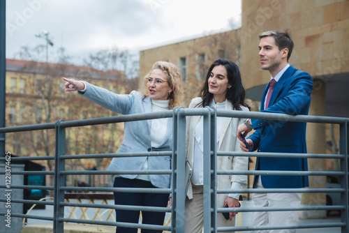 Businesswoman pointing while explaining something to her colleagues while standing next to a railing