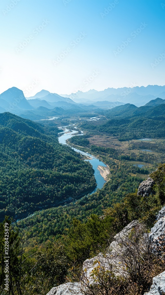 Naklejka premium Serene River Valley Amidst Majestic Mountains Under Bright Sky