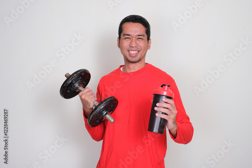 A sporty man smiling happy while holding dumbbell and drink tumbler photo