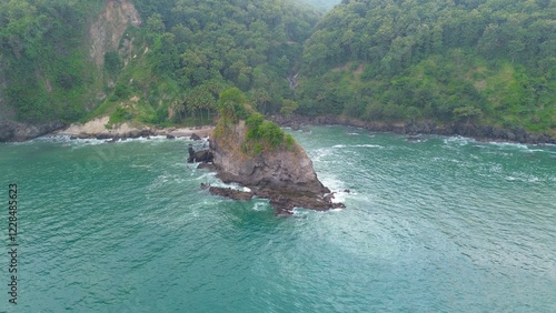 Aerial drone view of the coastline and seashore with rocks, hills and trees, beach sand and waves from the ocean at Karang Agung Beach, Kebumen, Central Java, Indonesia photo