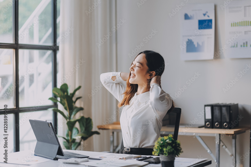 Office asian business woman stretching body for relaxing while working with laptop computer at her desk, office lifestyle, business situation Office asian business woman stretching body for relaxing while working with laptop computer at her desk, office lifestyle, business situation