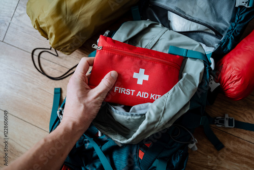 Fotografía A single individual is carefully placing a first aid kit into a backpack, ensuri
