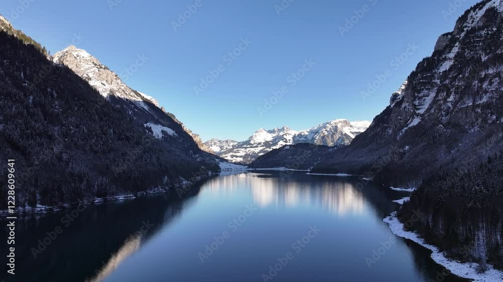 Breathtaking winter views of Klöntalersee in Klöntal, surrounded by Vorderglärnisch mountains, serene reflections and alpine beauty in Glarus, Switzerland.