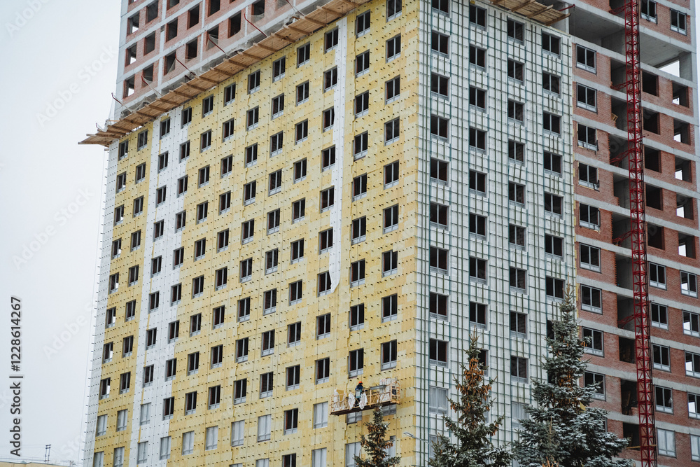Fototapeta premium A very tall building featuring an extensive number of windows is currently undergoing construction work in the bustling city area, contributing to the urban design and skyline