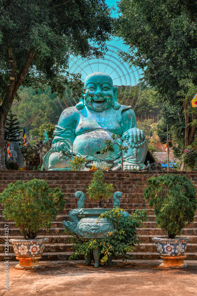 Smiling teal buddha statue surrounded by vegetation Smiling teal buddha statue surrounded by vegetation