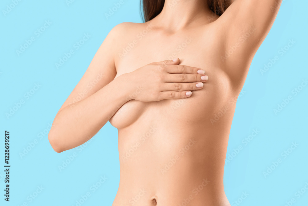 Naked young woman covering her breast on blue background Naked young woman covering her breast on blue background