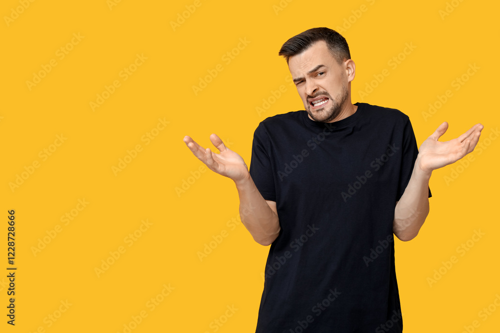 Handsome ashamed young man shrugging on yellow background Handsome ashamed young man shrugging on yellow background