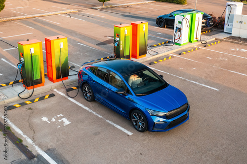Obraz na płótnie Modern vehicle receives electricity at public charging point. Parking lot equipped with plugs and connectors for quick replenishing of energy w salonie