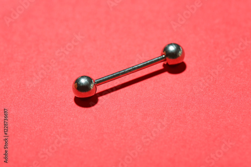 Silver barbell for piercing on red background photo