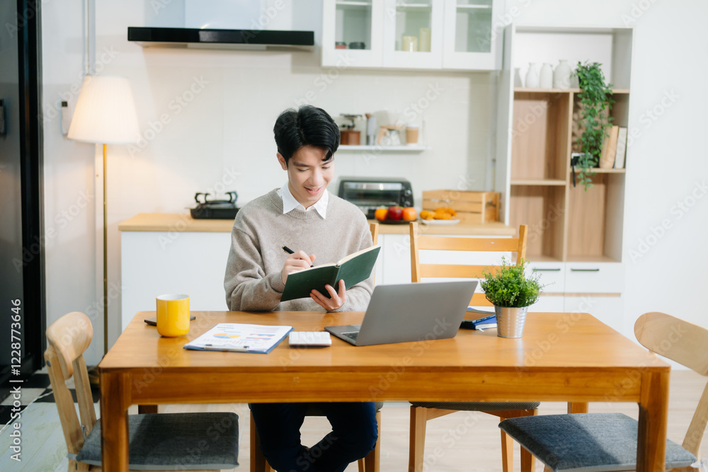 Young man using laptop while sitting at home. Young woman sitting in kitchen and working Young man using laptop while sitting at home. Young woman sitting in kitchen and working