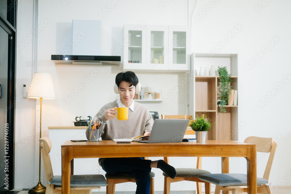 Young man using laptop while sitting at home. Young woman sitting in kitchen and working Young man using laptop while sitting at home. Young woman sitting in kitchen and working