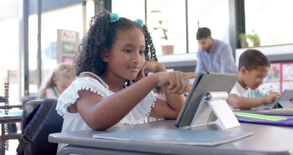 Biracial girl engaged with a tablet at school in a classroom Biracial girl engaged with a tablet at school in a classroom
