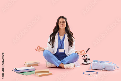 Young female medical student with books, microscope and backpack meditating o...