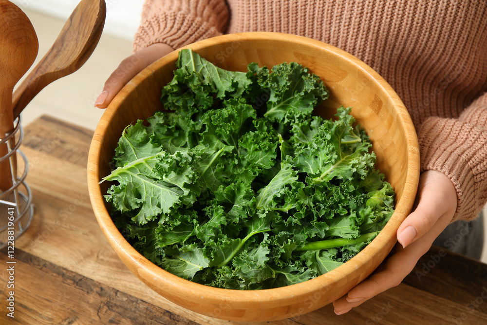 Woman with wooden bowl of fresh kale cabbage leaves in kitchen Woman with wooden bowl of fresh kale cabbage leaves in kitchen