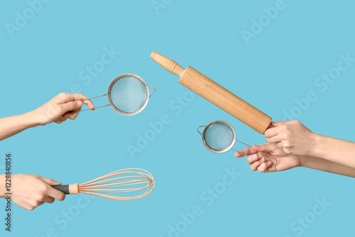 Female hands holding sieves with whisk and rolling pin on blue background photo