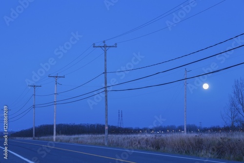 Highway bordered by hydro electricity distribution poles, moonrise at dusk, Quebec, Canada, North America photo