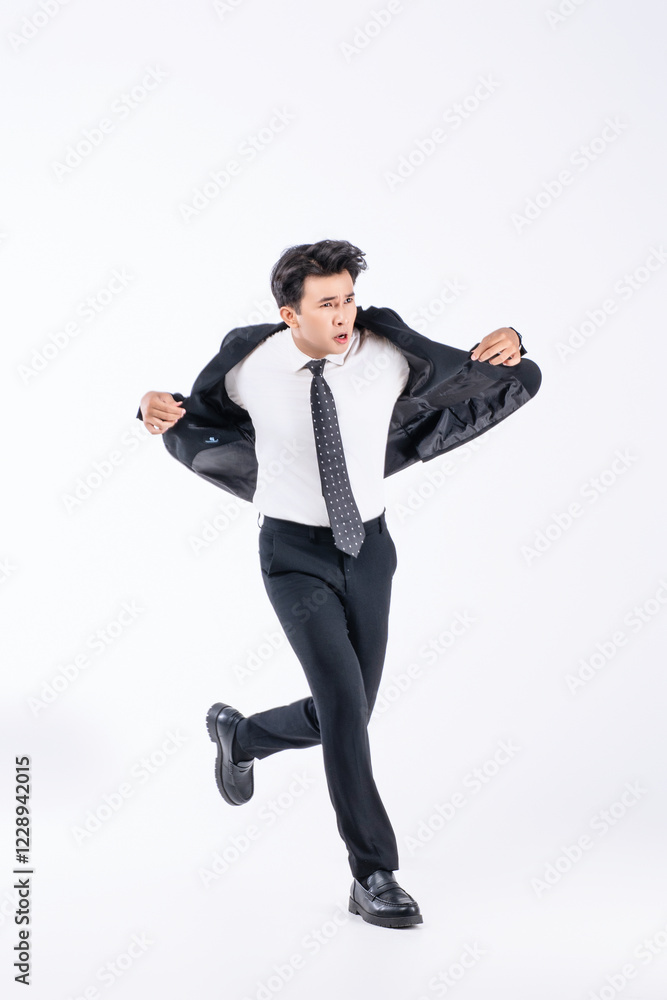 A man in a black suit and tie stands in front of a white background A man in a black suit and tie stands in front of a white background