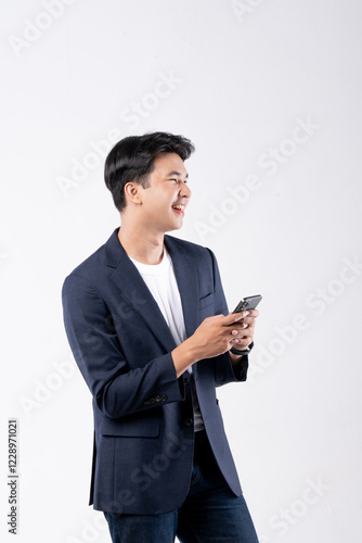 A man in a suit is smiling while looking at his cell phone
