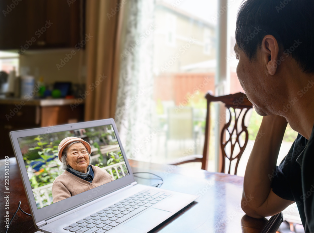 Man talking to elderly mother via video call.