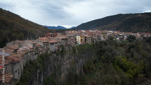Castellfollit de la Roca catalan town with little houses, cliffs and San Salvador church in Catalonia, Spain. High quality 4k drone footage