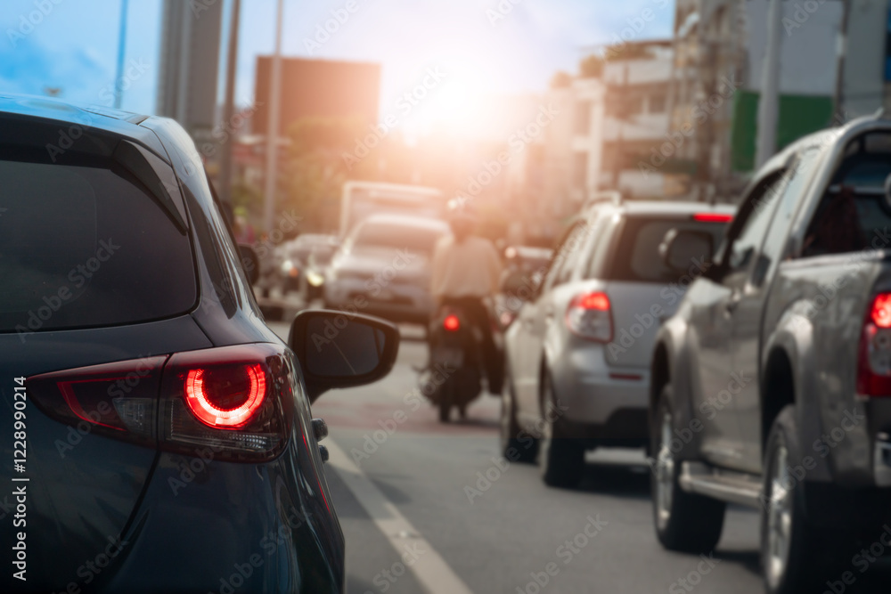 Rear side view of black car driving on the road. Background blurred of other cars under sky in the city. Cars lined up on the road in urgent traffic condition. Stop by traffic light. Rear side view of black car driving on the road. Background blurred of other cars under sky in the city. Cars lined up on the road in urgent traffic condition. Stop by traffic light.