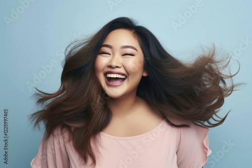 Lauging happy plus size curvy Asian woman in front of blue studio background. KI generiert, generiert AI generated photo