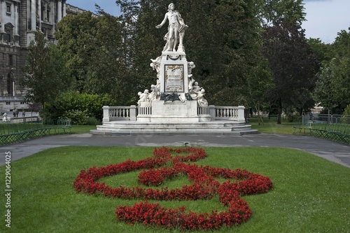 Photography Red flowers arranged as violin key with Mozart monument, Castle Garden, Vienna,