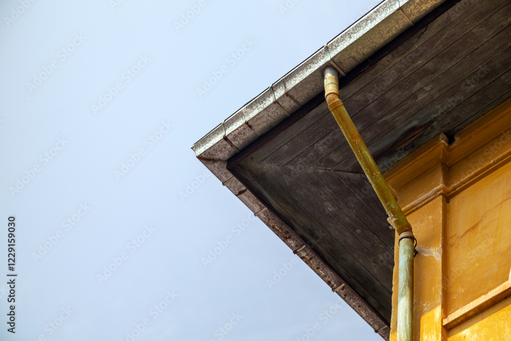 A striking perspective of a renovated building showcasing a galvanized roof, yellow-painted rusted pipes, and architectural elements that contrast modern and aged materials. A striking perspective of a renovated building showcasing a galvanized roof, yellow-painted rusted pipes, and architectural elements that contrast modern and aged materials.